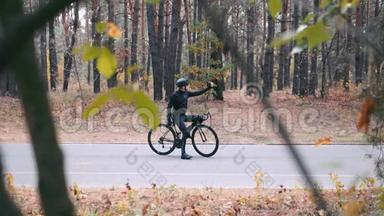 一位身穿黑色头盔的年轻职业自行车手正在打字，把<strong>手机</strong>放<strong>进口</strong>袋，开始骑在b路上